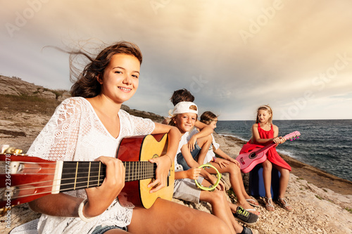 Girl playing guitar with her friends on the beach © Sergey Novikov