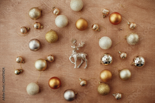 Merry Christmas. Christmas golden glitter reindeer and shiny baubles and balls on rustic background, flat lay. Modern gold decorations and present. Seasons greetings. Happy holidays