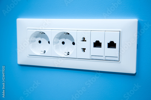 Socket electrical outlets for electrical plugs and electricity a set of different types of power connectors for European and American stanlart and connect the Internet cable close-up on the blue wall.