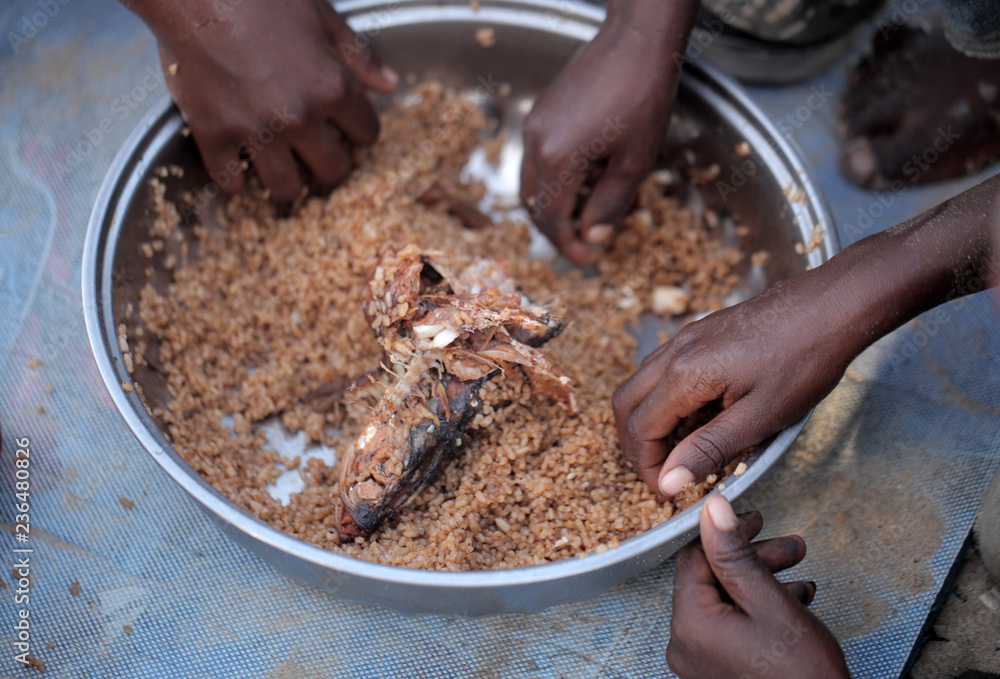 kids eating brown rice and fish in Africa - closeup