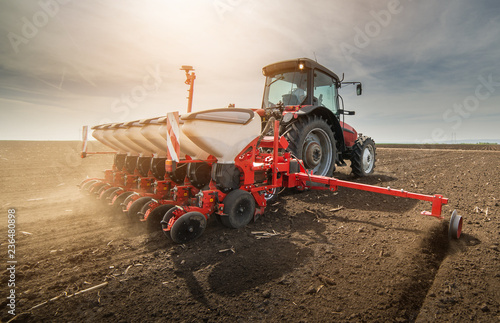  Farmer with tractor seeding sowing crops at agricultural field photo