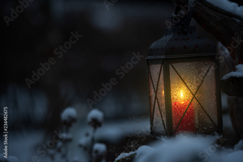 Candle lantern in the snowy garden at dusk. © ekim