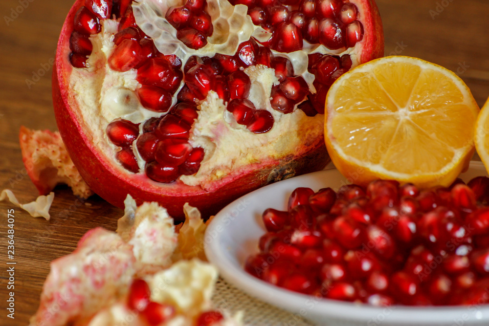 Ripe pomegranate and lemon on a ceramic plate. Close-up, wooden table and rustic background. Ripe pomegranate and lemon on a ceramic plate. Close-up, wooden table and rustic background.