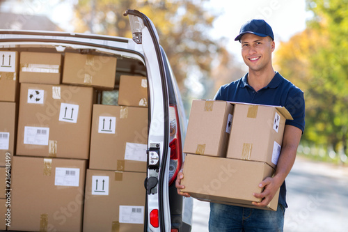 Fotografie Delivery man standing in front of his van
