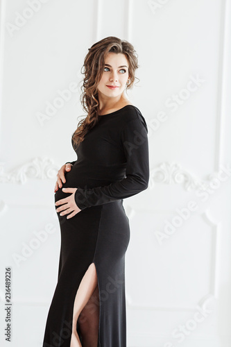Elegant pregnant woman wears long black dress