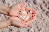 Female hand holding natural salt crystals on the background of a salt lake view from above