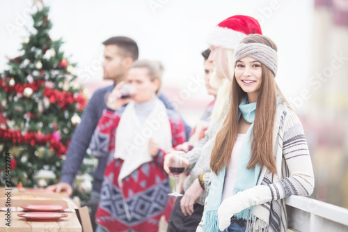 Young woman with friends on balcony celebrating Christmas