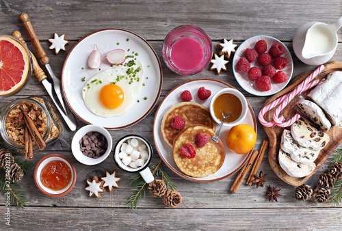 Christmas brunch or breakfast table. Festive brunch set, meal variety with fried egg, appetizers platter, pancakes, granola, smoothy and traditional sweets . Overhead view