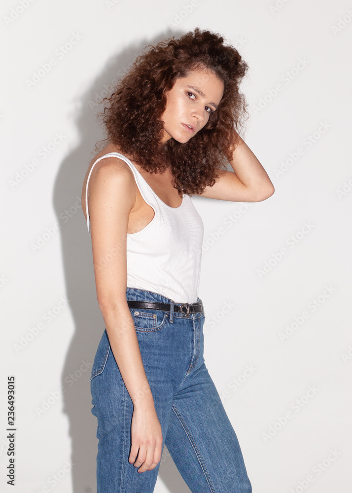 casual curly woman in jeans and white t-shirt, direct light, studio photo casual curly woman in jeans and white t-shirt, direct light, studio photo