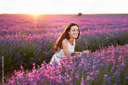 Woman standing between big violet lavender field at sunset photo