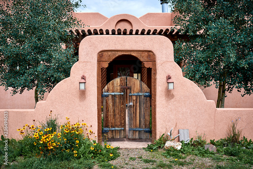 an adobe building with a wooden gate and wall