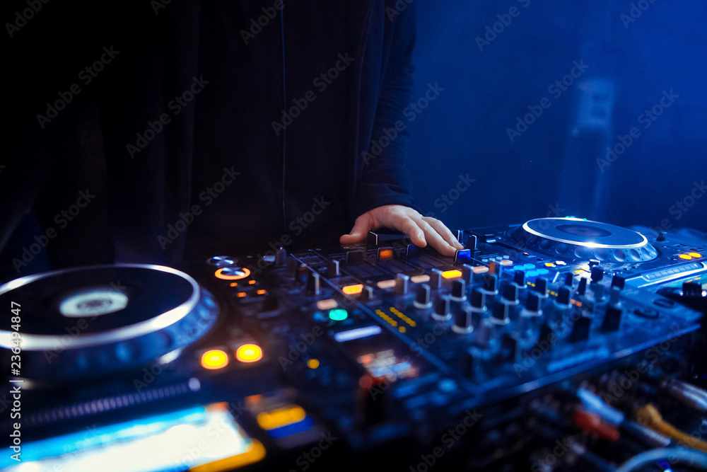 Obraz premium DJ turntable console mixer controlling with two hand in concert nightclub stage.