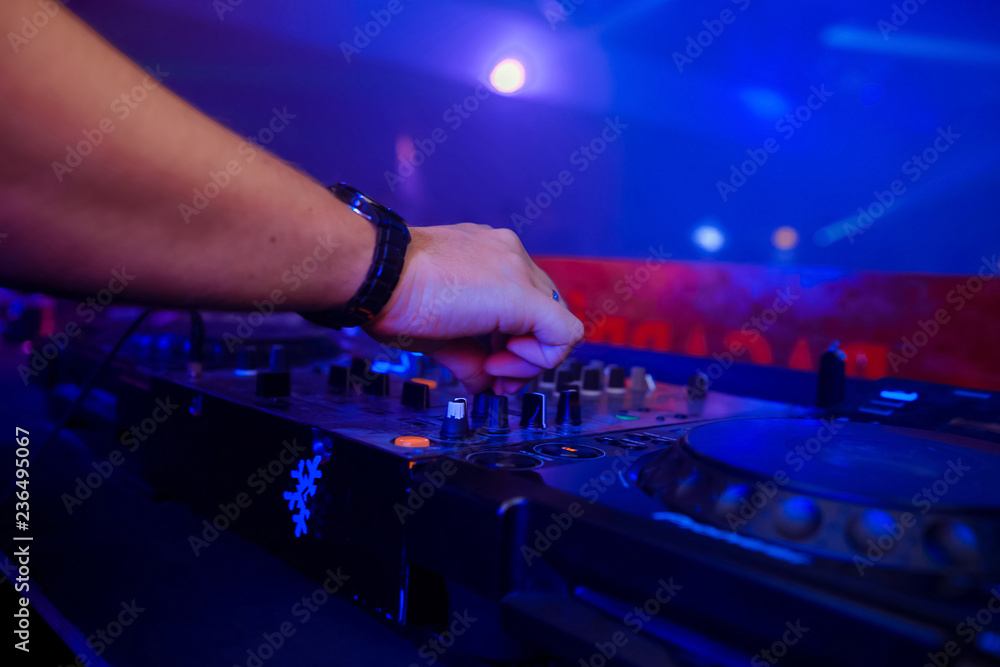 control DJ for mixing music with blurred people dancing at party in nightclub control DJ for mixing music with blurred people dancing at party in nightclub