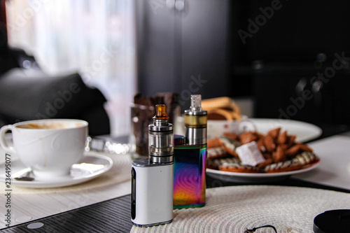 Electronic cigarette on club table in the living room.  Usually layout with electronic cigarettes and little things. Advanced model of electronic cigarette  e-cig