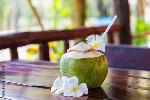 Fresh coconut cuts with tropical palm leaves and white frangipani flowers