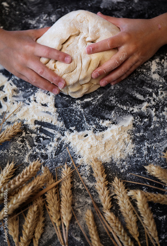 Knead the dough with wheat on dark background