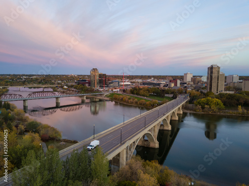 Aerial view of a bridge going over Saskatchewan River during a vibrant sunrise in the Fall Season. Taken in Saskatoon, SK, Canada.