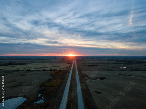 Aerial view of the Highway in the Prairies during a vibrant cloudy sunset. Taken East of Edmonton, Alberta, Canada.