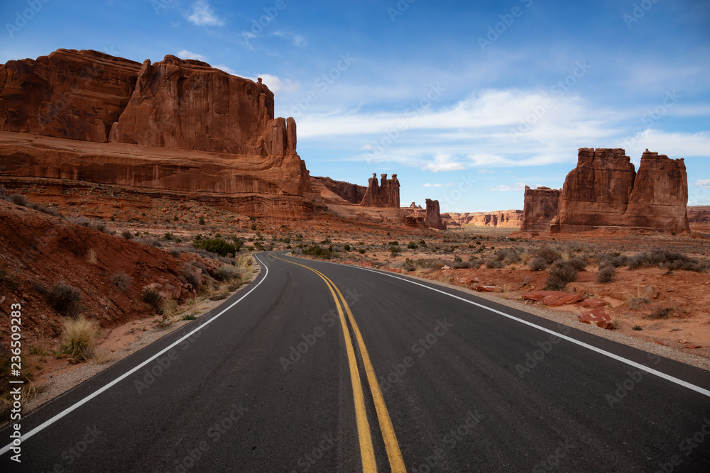 Landscape view of a Scenic road in the red rock canyons during a vibrant sunny day. Taken in Arches National Park, located near Moab, Utah, United States. Landscape view of a Scenic road in the red rock canyons during a vibrant sunny day. Taken in Arches National Park, located near Moab, Utah, United States.