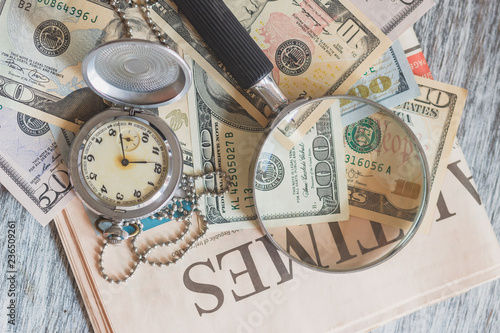 Pocket watch, American dollars and a magnifying glass
