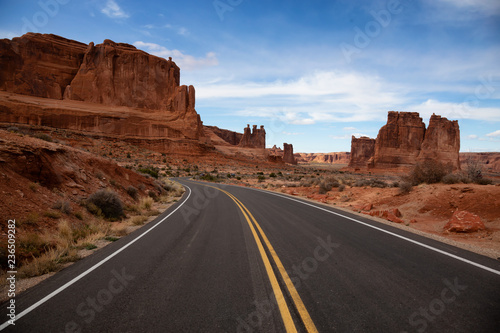 Landscape view of a Scenic road in the red rock canyons during a vibrant sunny day. Taken in Arches National Park, located near Moab, Utah, United States.