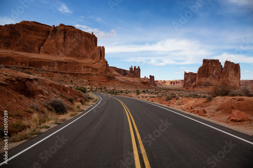Landscape view of a Scenic road in the red rock canyons during a vibrant sunny day. Taken in Arches National Park, located near Moab, Utah, United States. photo