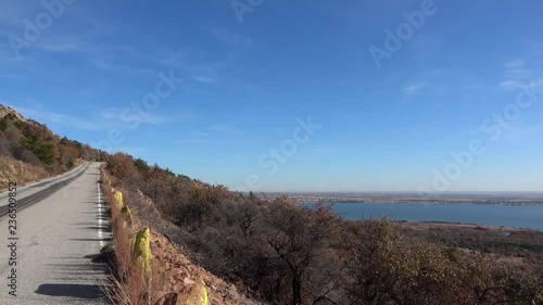 View of beautiful landscape with road, lake and autumn colors of wild growing trees and brush. View from Wichita Mountains.
