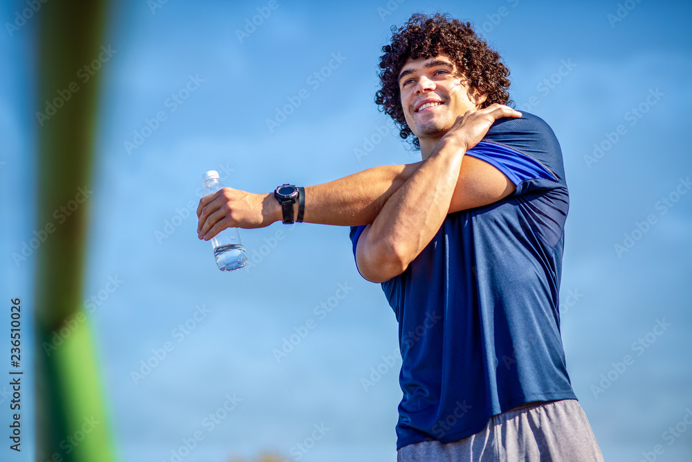 Fototapeta premium Running stretching - Sportsman running doing exercises in the park..
