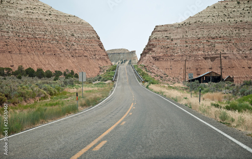 Road with traffic sign and barn near red rock canyon, USA