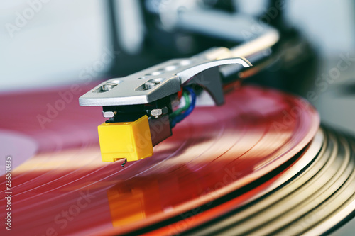 Turntable vinyl record player. Sound technology for DJ to mix and play music. Stylus with a needle on a vinyl record. Red vinyl. Label. Bright party lights illuminate the surface of the plate