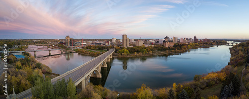 Aerial panoramic view of a bridge going over Saskatchewan River during a vibrant sunrise in the Fall Season. Taken in Saskatoon, SK, Canada. photo