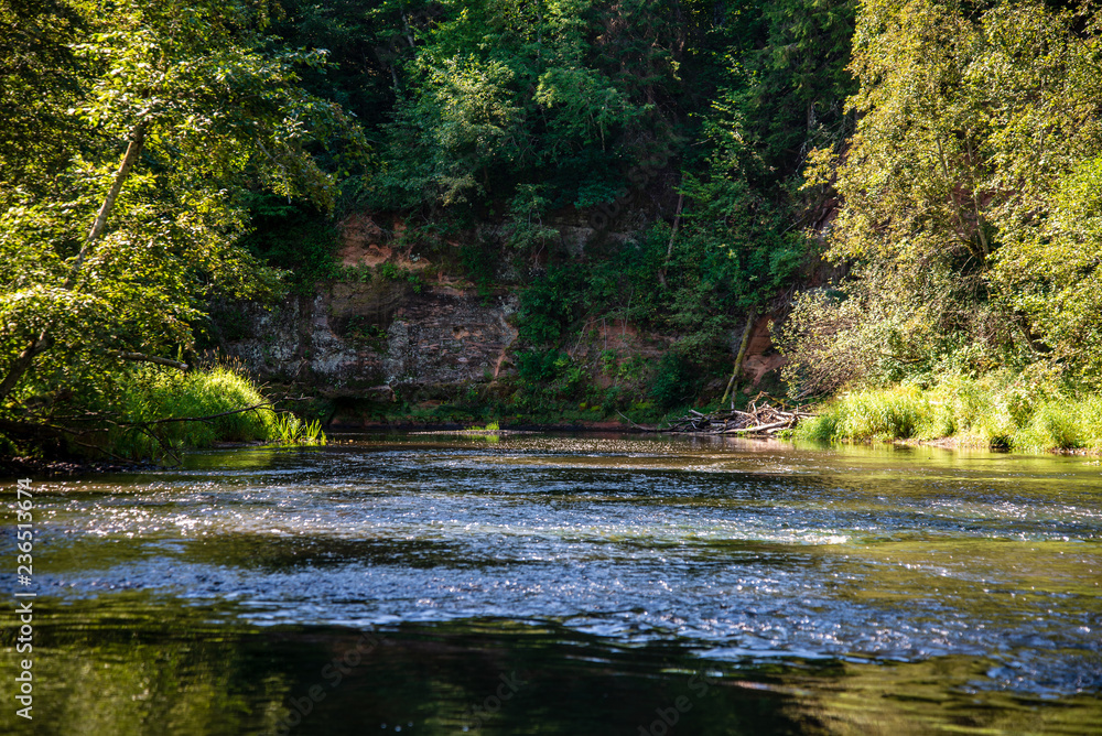 summer day on water in calm river enclosed in forests with sandstone cliffs and dry wood summer day on water in calm river enclosed in forests with sandstone cliffs and dry wood