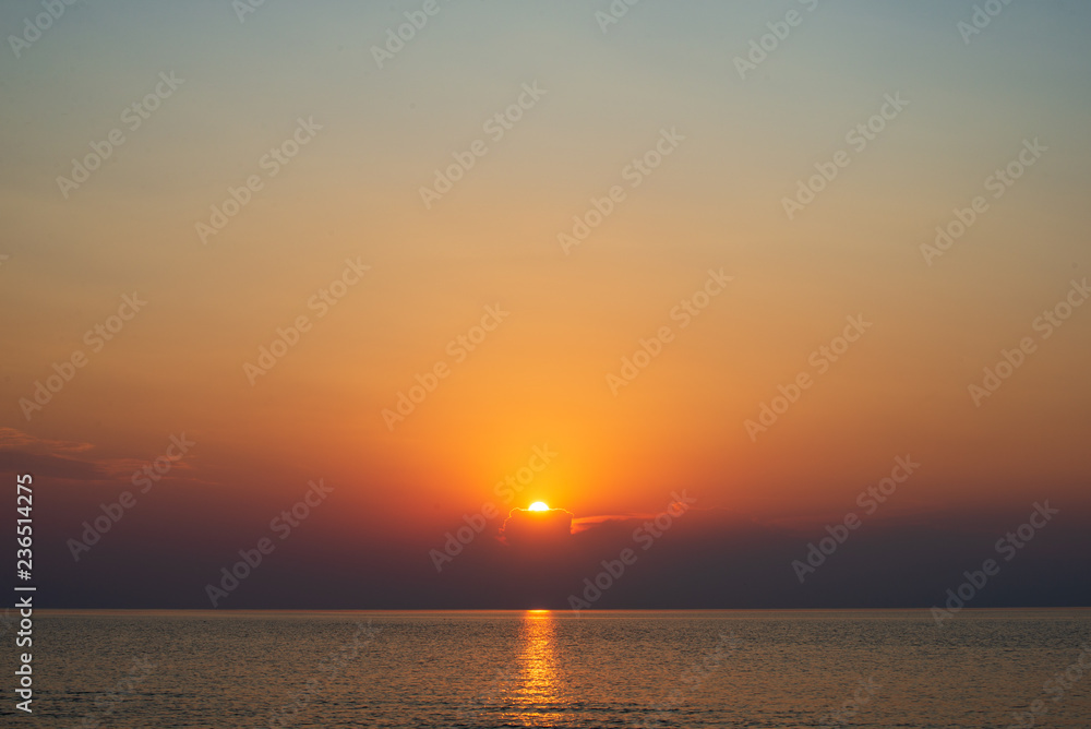 Fototapeta premium dramatic red orange colored sunset over the calm sea at summer