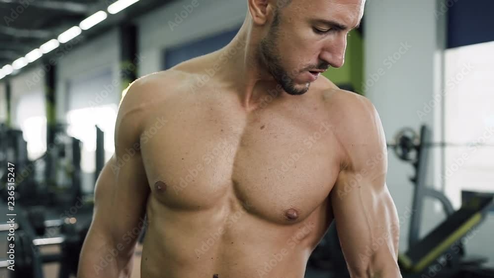 Hard working man with naked torso working out with dumbbells for pumping muscle arms in the gym. Hard working man with naked torso working out with dumbbells for pumping muscle arms in the gym.