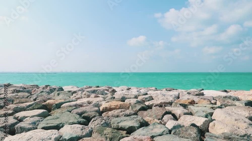 A shot of the sea crashing against the rocks on a windy, sunny day on the palm in Dubai photo