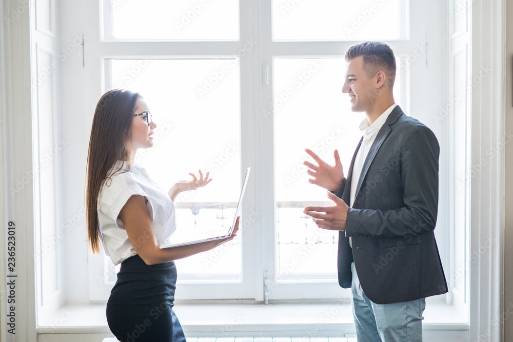 Fototapeta premium Business man and business woman discuss informal near the office building windows.