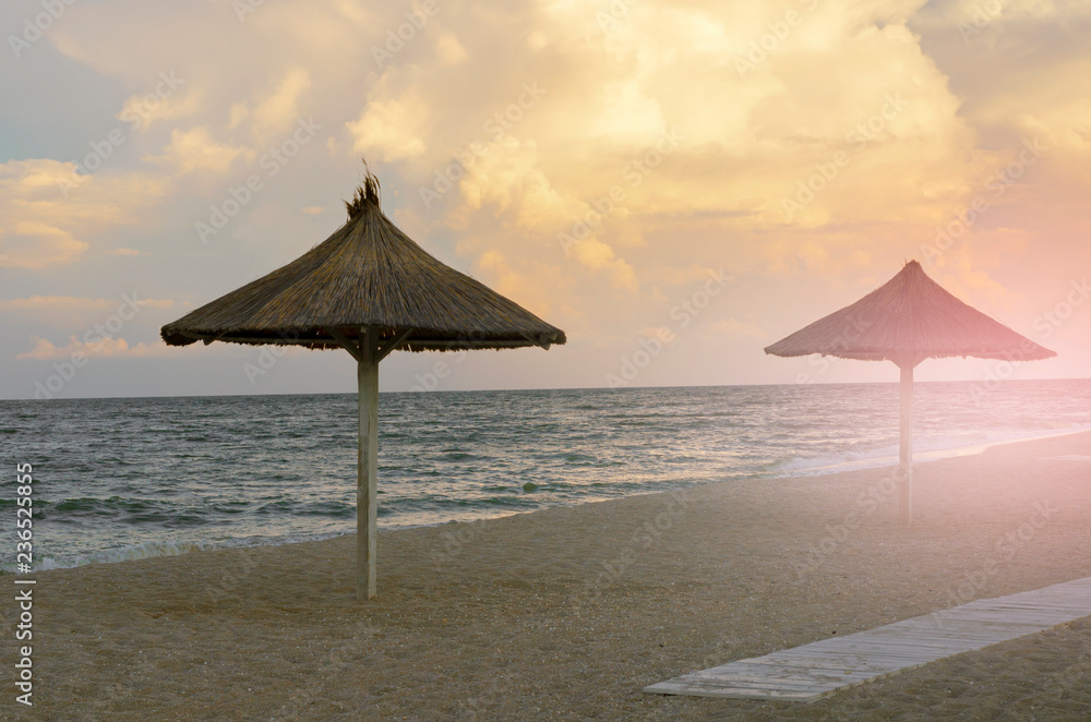 sunset on the beach. beach straw umbrellas on the sea coast. End of the beach season. empty beach sunset on the beach. beach straw umbrellas on the sea coast. End of the beach season. empty beach