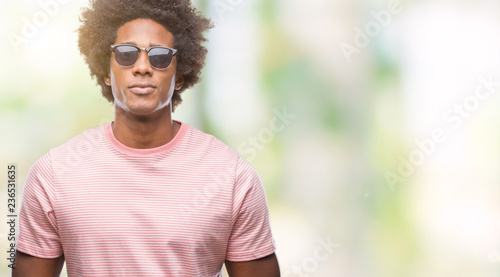 Afro american man wearing sunglasses over isolated background with serious expression on face. Simple and natural looking at the camera.