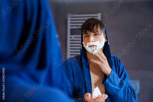 Young man shaving in bathroom photo