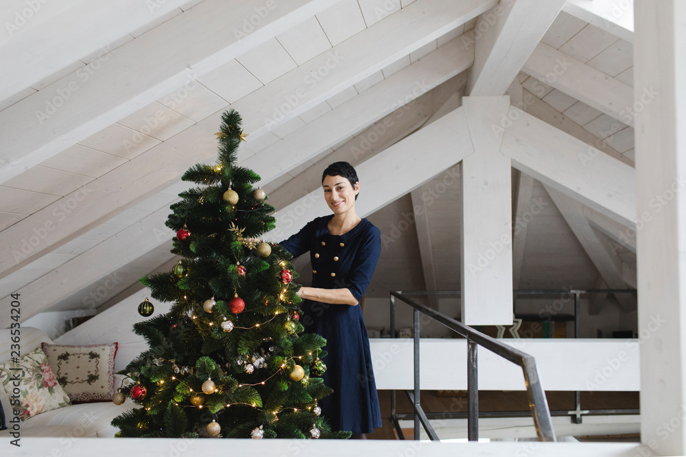 Brunette woman decorating Christmas tree Brunette woman decorating Christmas tree