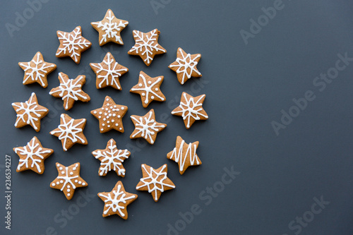 Fototapeta Naklejka Na Ścianę i Meble -  Group of snowflake shaped gingerbread cookies arranged in a circle, flat lay on the black background with copy space.CR2