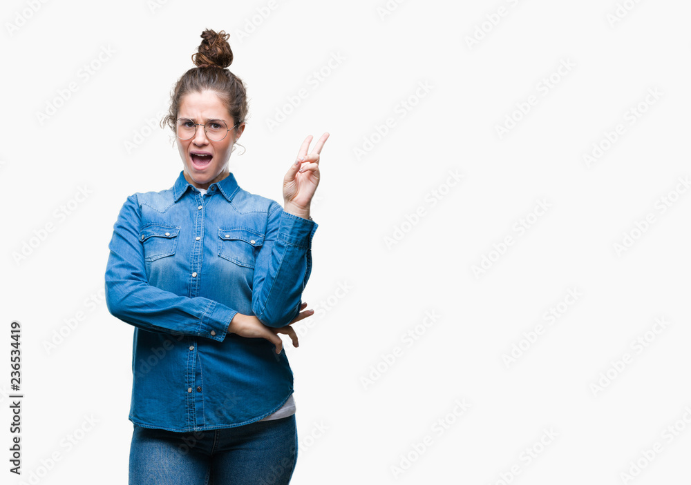 Beautiful young brunette curly hair girl wearing glasses over isolated background smiling with happy face winking at the camera doing victory sign. Number two. Beautiful young brunette curly hair girl wearing glasses over isolated background smiling with happy face winking at the camera doing victory sign. Number two.