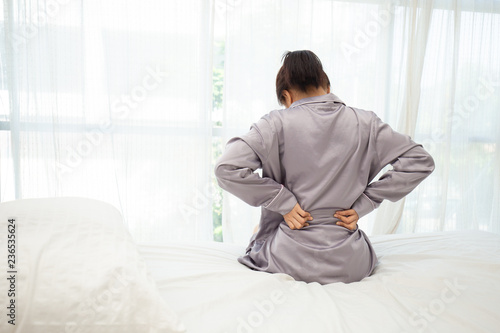 woman have a back pain sitting on bed after wake up in bedroom,Healthcare Concept