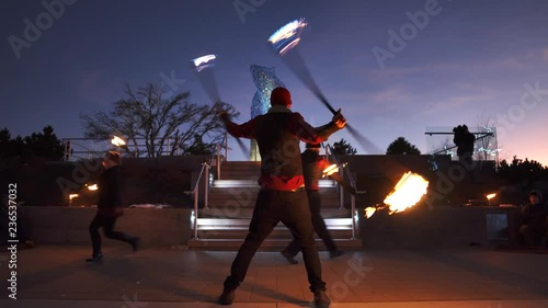 Public fire performance with man spinning two large fire staffs photo