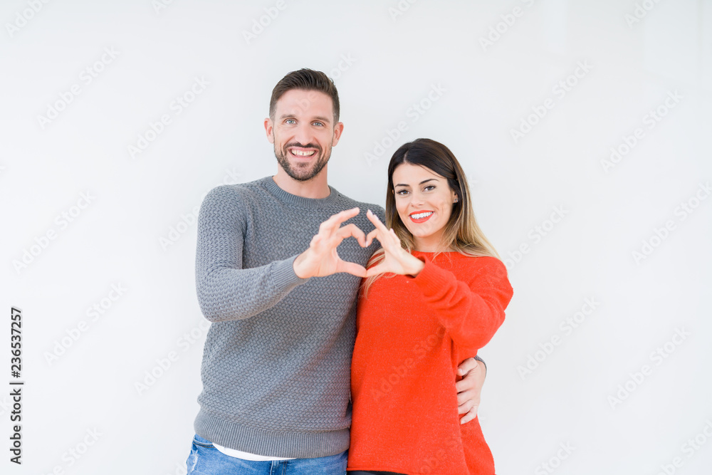 Young beautiful couple togheter over isolated background smiling in love showing heart symbol and shape with hands. Romantic concept. Young beautiful couple togheter over isolated background smiling in love showing heart symbol and shape with hands. Romantic concept.