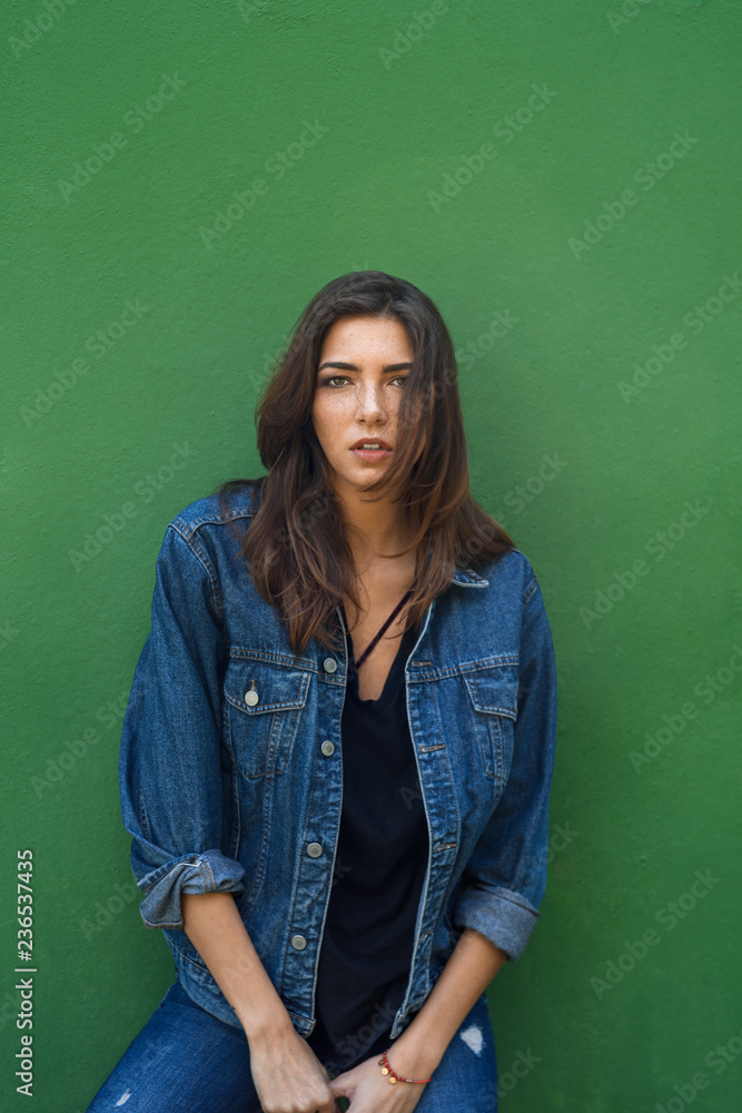 Sensual beautiful brunette in denim jacket over green background Sensual beautiful brunette in denim jacket over green background