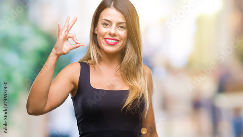 Young beautiful woman over isolated background smiling positive doing ok sign with hand and fingers. Successful expression.