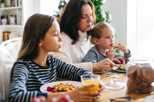 Mother and her daughters eating breakfast on Christmas morning.  photo