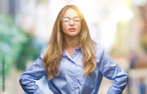Young beautiful blonde business woman wearing glasses over isolated background winking looking at the camera with sexy expression, cheerful and happy face.