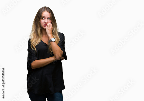 Young beautiful blonde woman over isolated background looking stressed and nervous with hands on mouth biting nails. Anxiety problem.